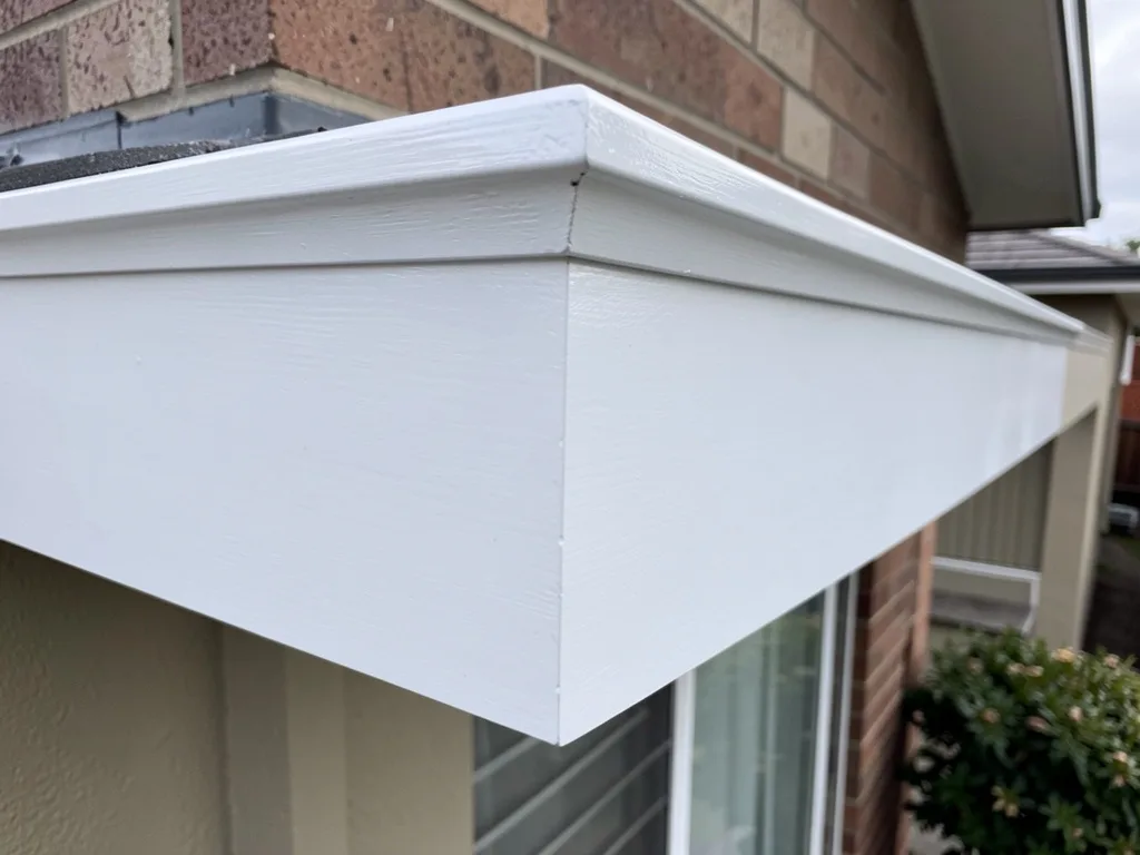 Close-up detail of a repainted white fascia corner on a Melbourne brick home, crisp clean lines, natural daylight, no people or tools in frame.