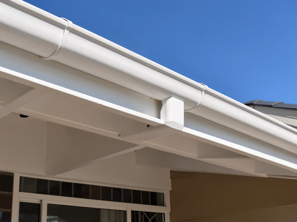 A freshly painted white gutter and fascia line along a Melbourne home roofline, clean crisp finish against a blue sky, no people or ladders in frame.