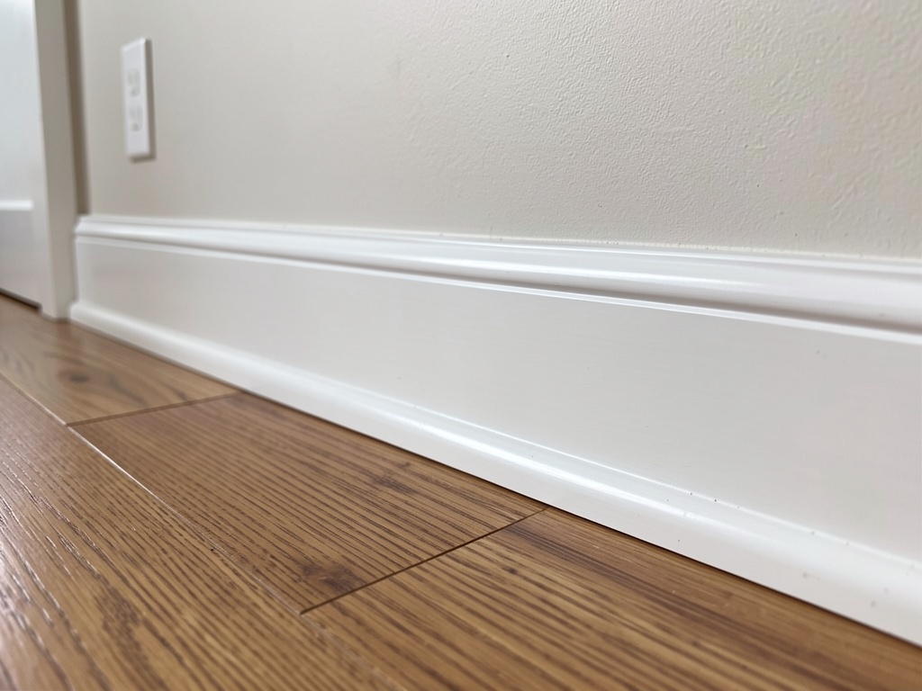 White painted skirting boards with a clean gloss finish on timber flooring