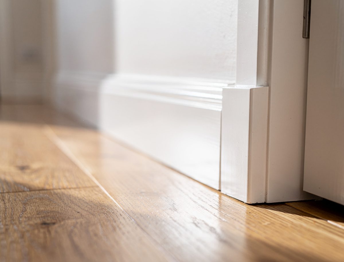 Close-up of freshly painted white skirting board and architrave meeting light oak timber flooring in an Aintree home