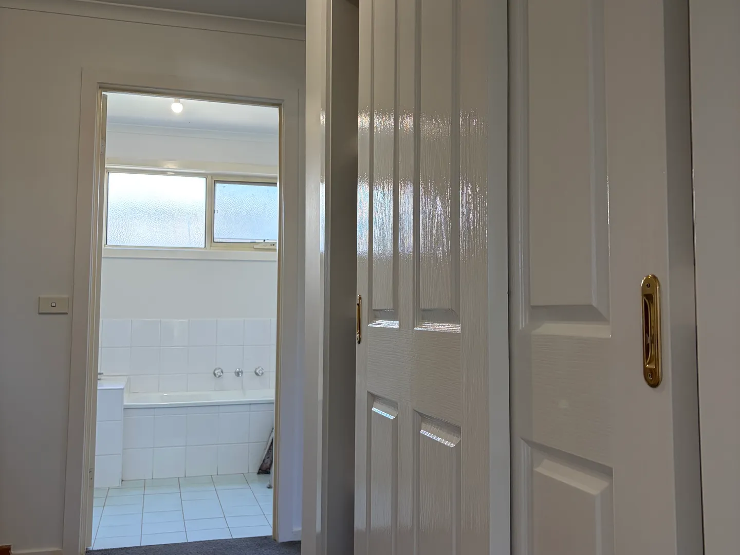 Hallway with white enamel doors and a bathroom doorway in a two-storey Maidstone townhouse, painted by Modernize Solutions
