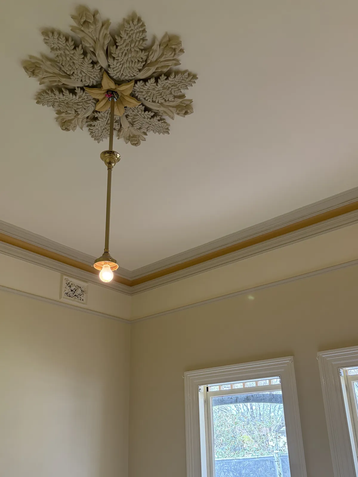 Period room with ornate ceiling rose, brass pendant light, two-tone cornice, picture rail and white window frames, interior painting by Modernize Solutions