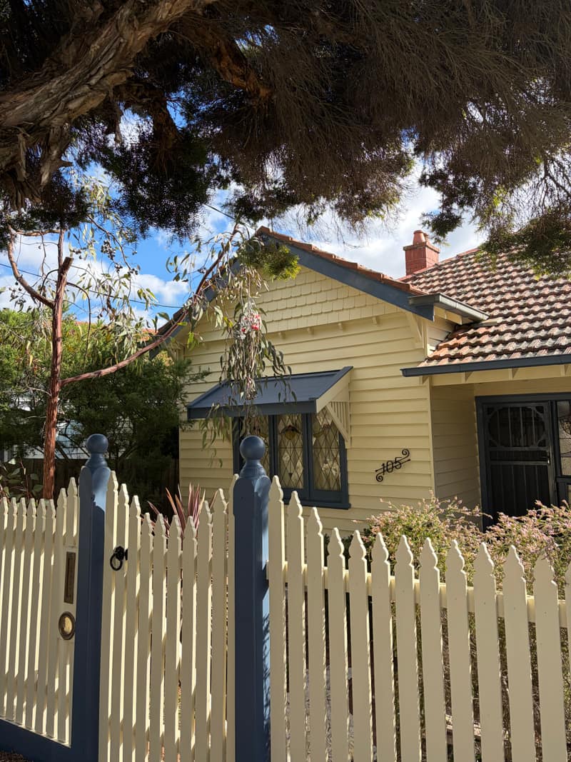 Repainted Melbourne weatherboard home, cream facade with deep blue trim and leadlight bay window