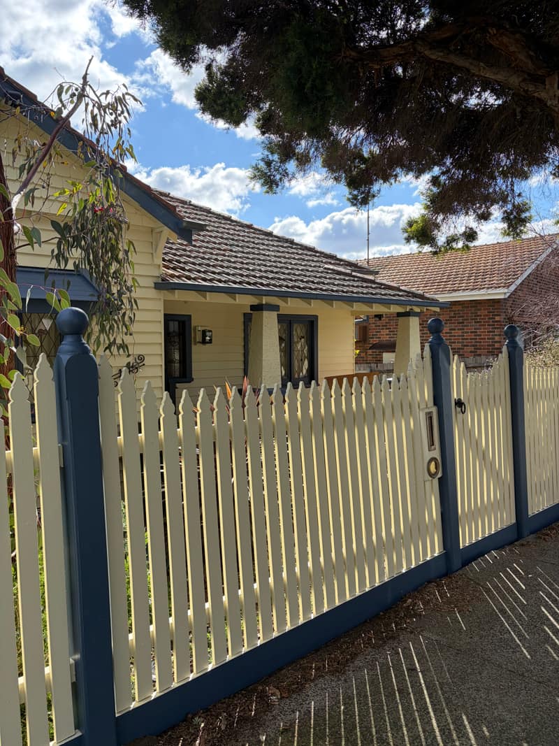 The same picket fence and gate repainted cream with deep blue posts