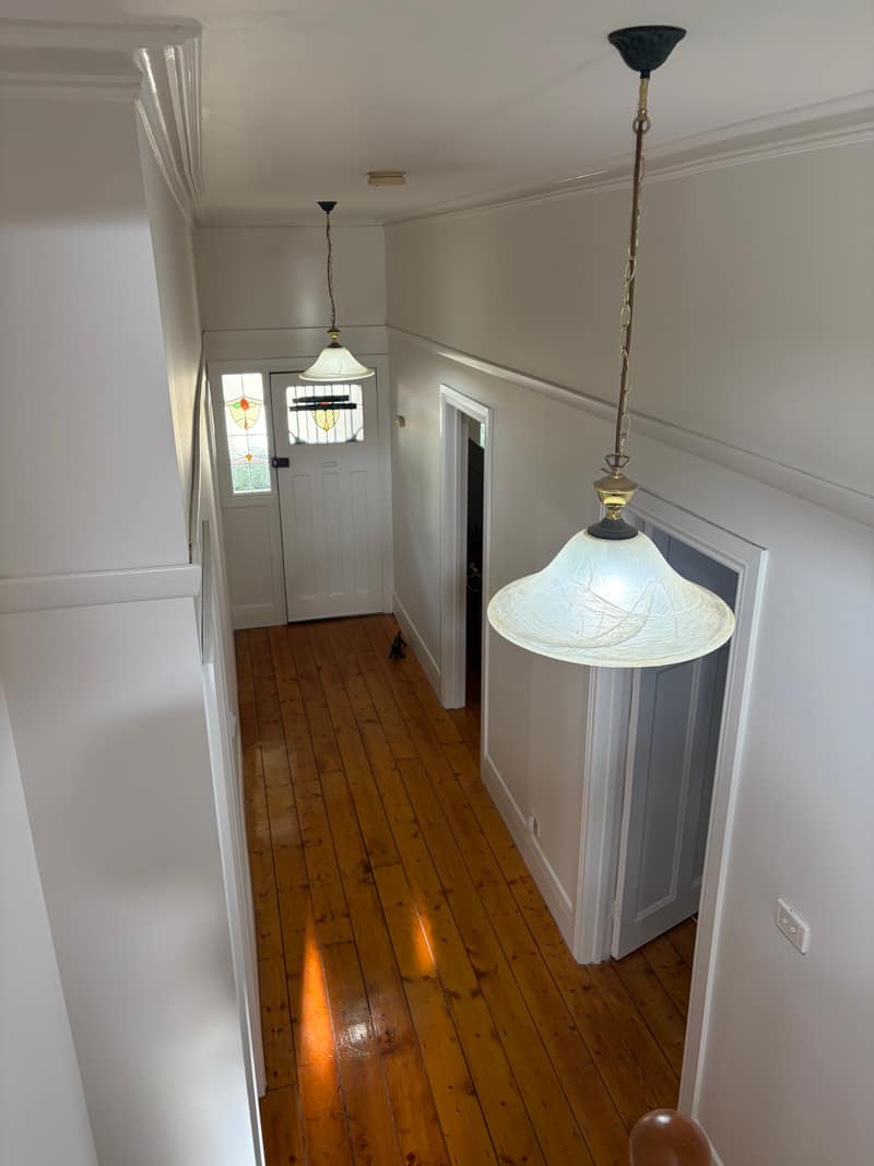 The same hallway repainted white above polished floorboards