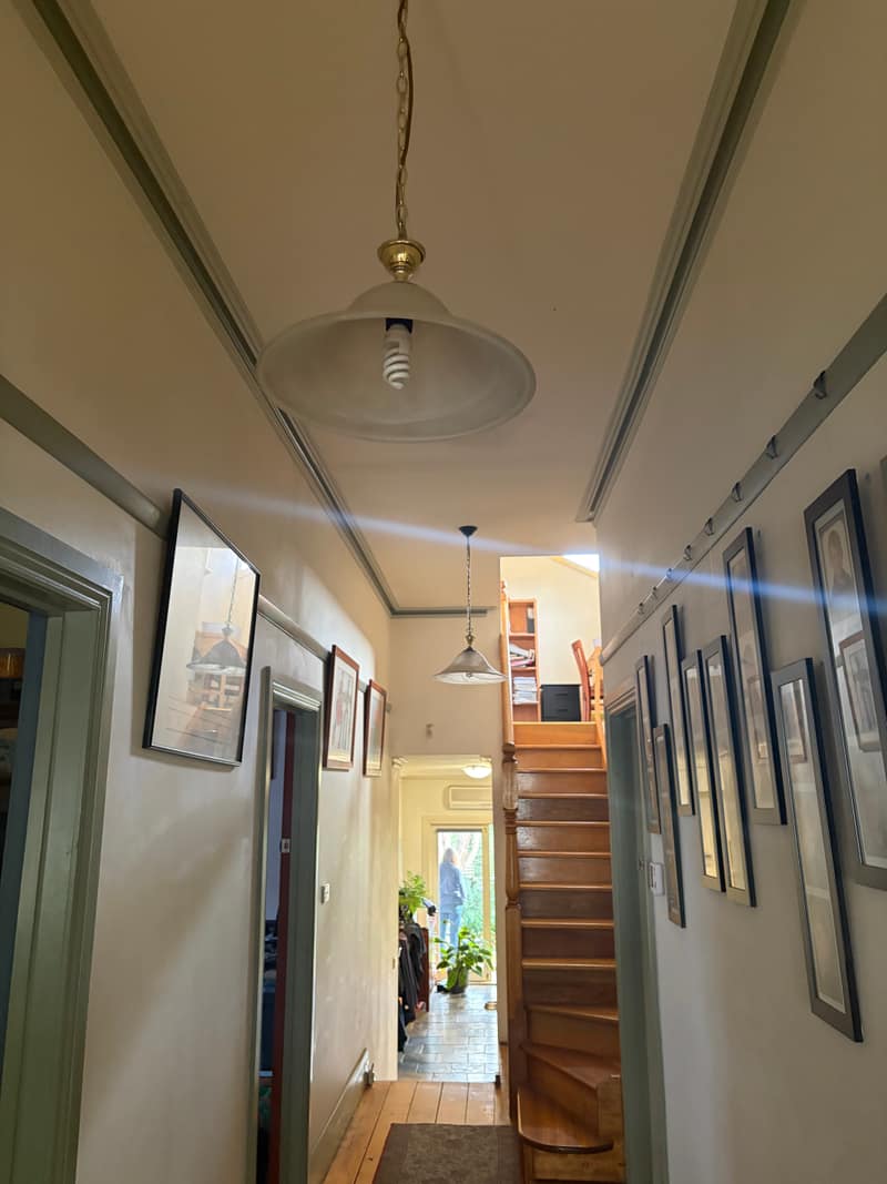 Dim hallway with dated wall and trim colours before interior painting