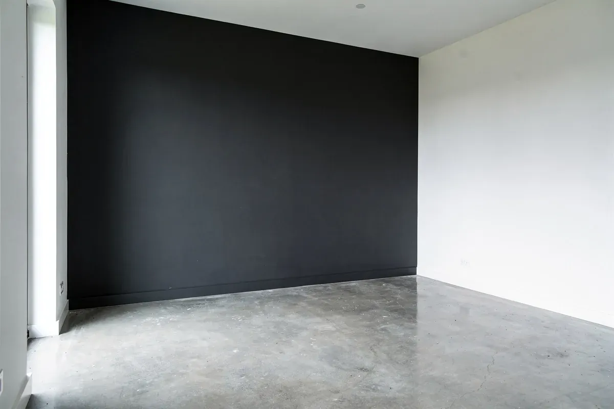 Charcoal feature wall with crisp edge against white walls and polished concrete floor in a modern Melbourne home